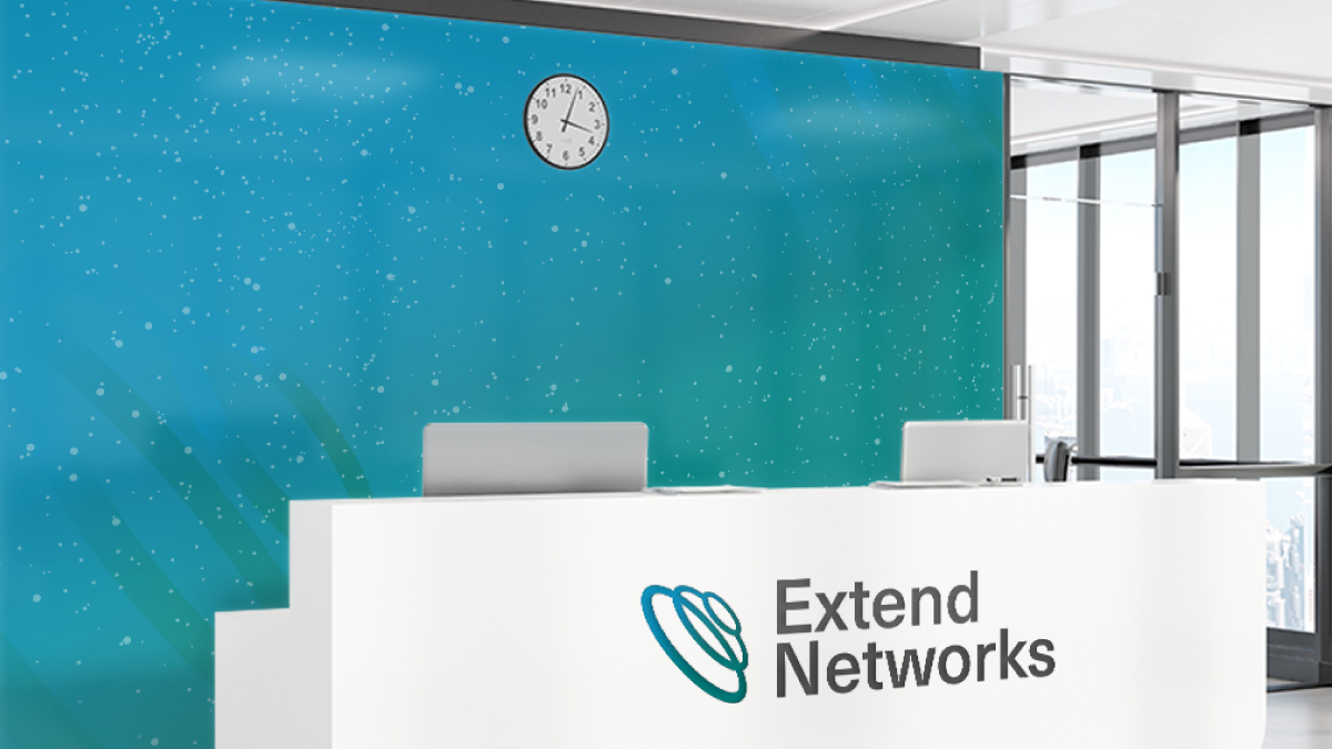 Extend Networks reception area with a white desk featuring the logo, set against a teal wall with a clock. Large windows provide natural light to the space