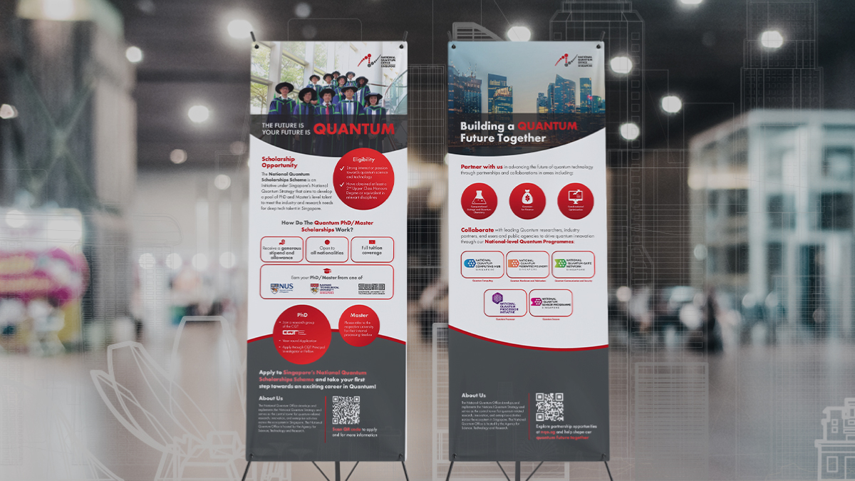 Two National Quantum Office (NQO) X-stand banners erected in a modern exhibition hall with blurred background lights and booths. Left banner: Diverse youth group photo, red circular icons, structured text sections, QR code. Right banner: "Building a Quantum Future Together" headline, heart and blood drop icons, partner logos in blue circles, QR code. Red and gray design scheme creates immersive environmental branding for quantum research showcase.